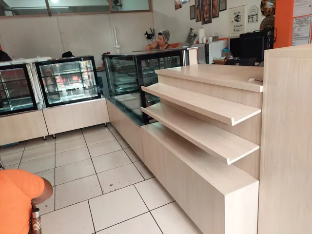 Vitrines expositoras e balcão com prateleiras em madeira clara em padaria